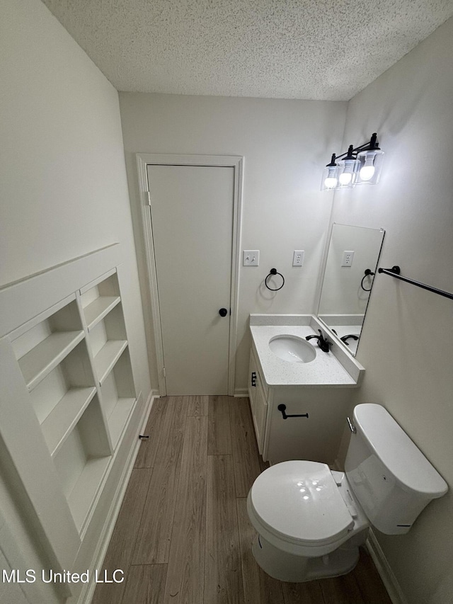 747 Cumberland Cv, Southaven, MS 38671 - bathroom with toilet, vanity, wood finished floors, a textured ceiling, and baseboards