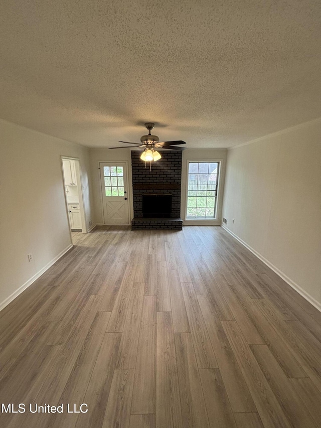 747 Cumberland Cv, Southaven, MS 38671 - unfurnished living room with a fireplace, wood finished floors, a textured ceiling, baseboards, and ceiling fan