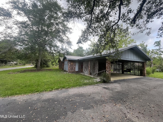 14920 Garrett St, Ocean Springs, MS 39565 - view of front of house with driveway, a front lawn, board and batten siding, an attached carport, and metal roof
