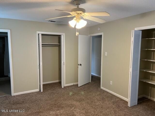 unfurnished bedroom featuring carpet floors, two closets, and ceiling fan