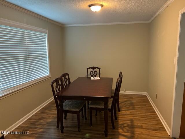 dining room featuring crown molding, a textured ceiling, and dark wood-type flooring