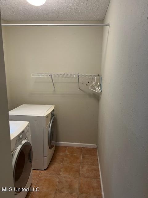 clothes washing area featuring a textured ceiling, washer and clothes dryer, and tile patterned flooring