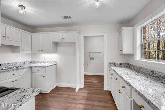 kitchen featuring light stone countertops, visible vents, white cabinets, and a sink