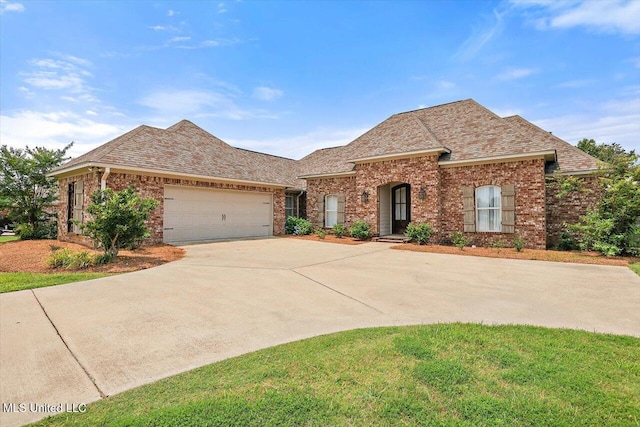 153 Hampton Hills Blvd, Canton, MS 39046 - french country home with brick siding, concrete driveway, a garage, roof with shingles, and a front lawn