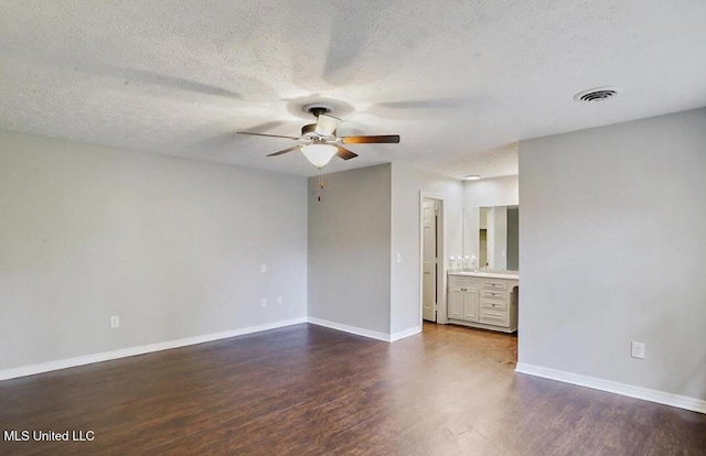 spare room featuring visible vents, dark wood-type flooring, a ceiling fan, a textured ceiling, and baseboards