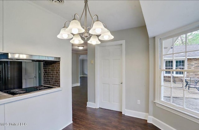 unfurnished dining area with baseboards, an inviting chandelier, and wood finished floors