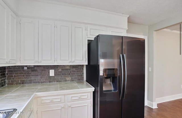 kitchen featuring white cabinetry, decorative backsplash, tile countertops, and stainless steel fridge with ice dispenser