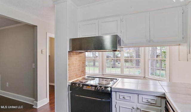 kitchen featuring backsplash, light countertops, range hood, white cabinets, and black / electric stove