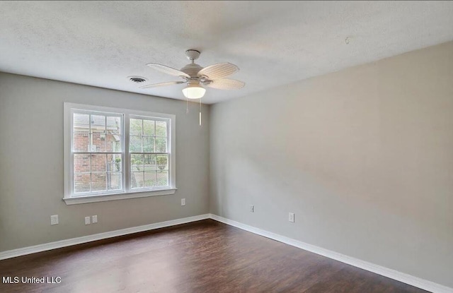 spare room featuring visible vents, a ceiling fan, a textured ceiling, baseboards, and dark wood-style flooring