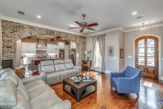 living room featuring a healthy amount of sunlight, brick wall, ceiling fan with notable chandelier, and hardwood / wood-style flooring