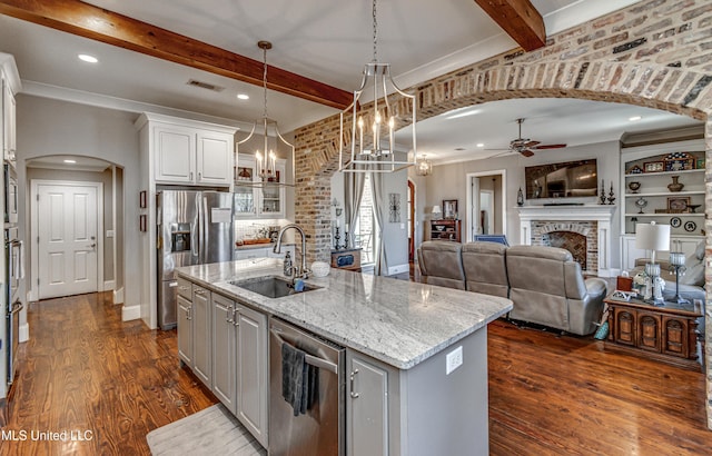 kitchen featuring pendant lighting, appliances with stainless steel finishes, a fireplace, sink, and a center island with sink