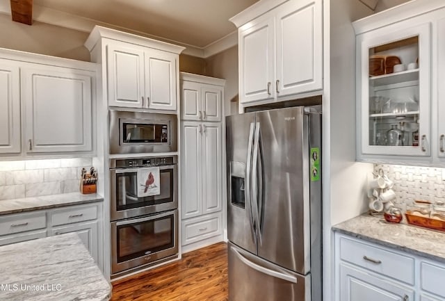 kitchen featuring hardwood / wood-style floors, appliances with stainless steel finishes, decorative backsplash, and white cabinets