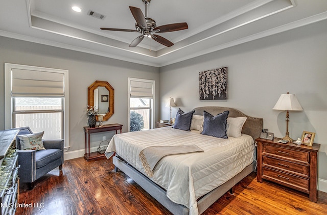 bedroom featuring dark hardwood / wood-style floors, ceiling fan, crown molding, and a raised ceiling