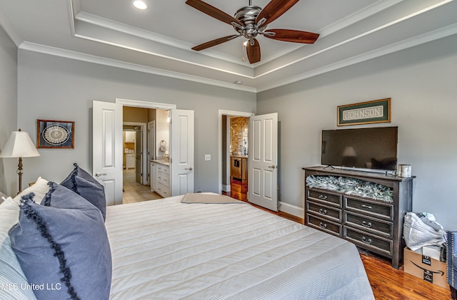 bedroom with ceiling fan, ensuite bath, ornamental molding, and a raised ceiling