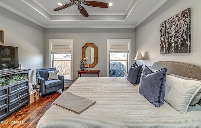 bedroom with ceiling fan, dark hardwood / wood-style flooring, ornamental molding, and a raised ceiling