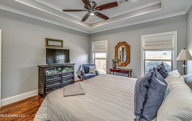 bedroom featuring dark hardwood / wood-style floors, ceiling fan, crown molding, and a raised ceiling