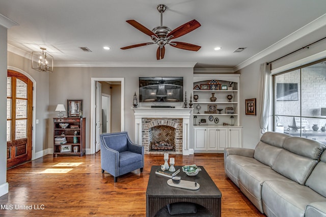 living room featuring hardwood / wood-style flooring, plenty of natural light, ceiling fan with notable chandelier, and a fireplace