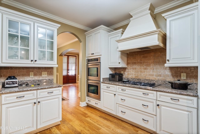 4788 Bon Jour Ln, Nesbit, MS 38651 - kitchen with appliances with stainless steel finishes, arched walkways, custom exhaust hood, light wood-style flooring, and crown molding