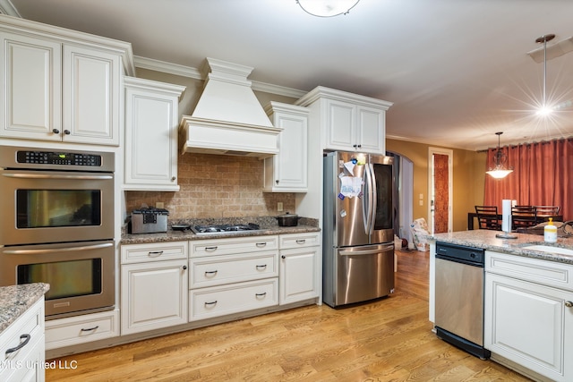 4788 Bon Jour Ln, Nesbit, MS 38651 - kitchen with appliances with stainless steel finishes, custom exhaust hood, arched walkways, light wood finished floors, and decorative backsplash