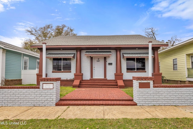 bungalow with brick siding, a porch, and a shingled roof