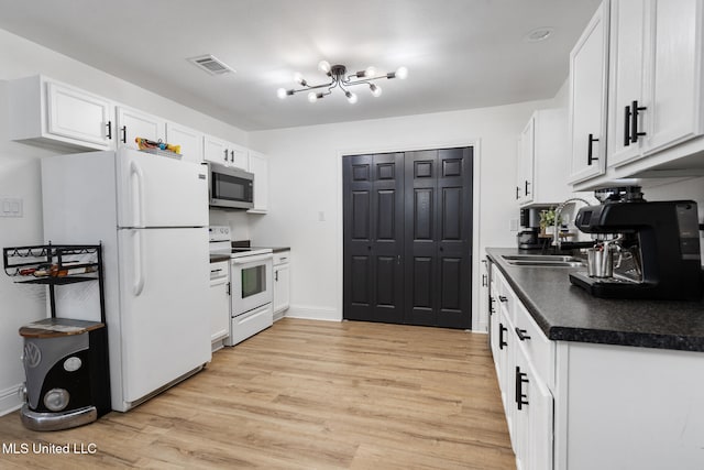 kitchen featuring white appliances, visible vents, white cabinets, dark countertops, and a sink