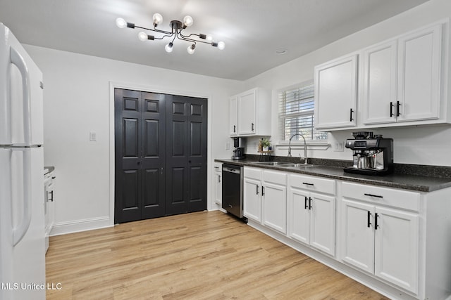 kitchen featuring a sink, light wood-style floors, stainless steel dishwasher, freestanding refrigerator, and dark countertops