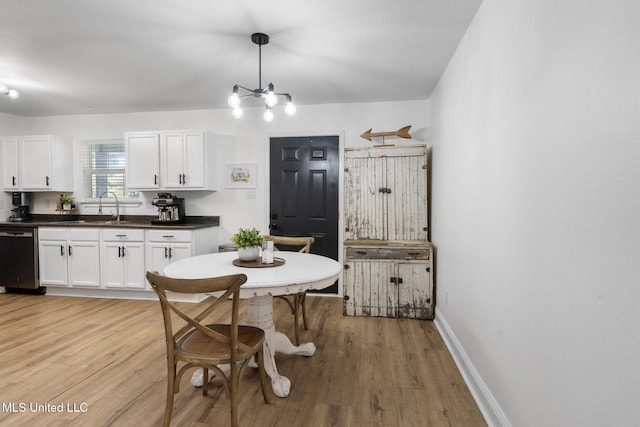 dining room with a notable chandelier, light wood-style flooring, and baseboards