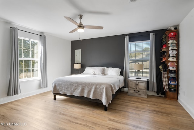 bedroom with ceiling fan, multiple windows, and light wood-type flooring