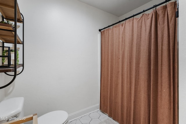 full bath with toilet, baseboards, and tile patterned floors