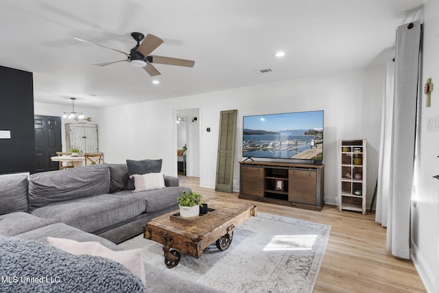 living area with light wood finished floors, recessed lighting, visible vents, baseboards, and ceiling fan with notable chandelier