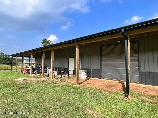 rear view of house with ac unit, an outdoor structure, and a yard