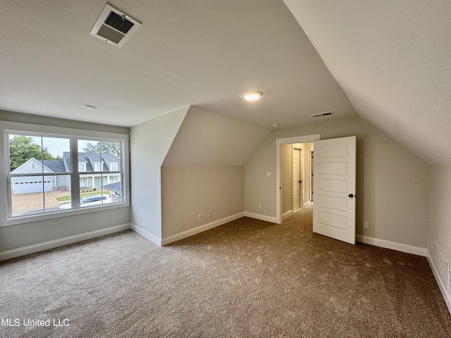 additional living space featuring vaulted ceiling and dark colored carpet