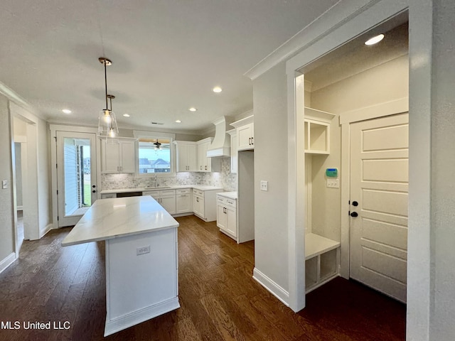 kitchen featuring a kitchen island, white cabinetry, pendant lighting, premium range hood, and dark hardwood / wood-style floors