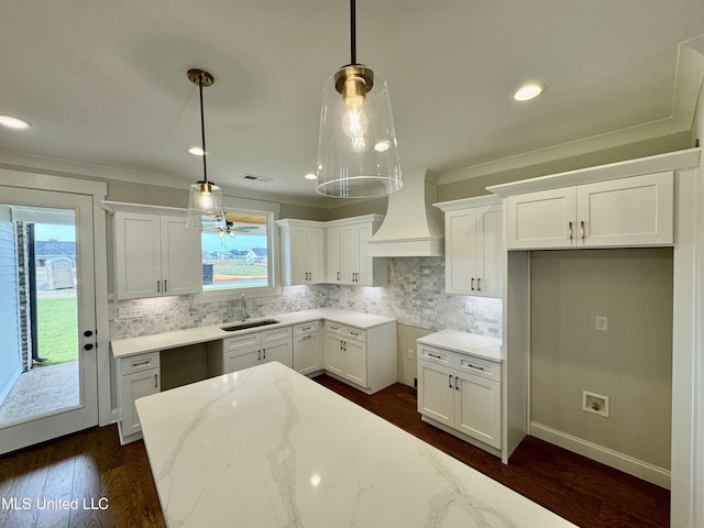 kitchen featuring white cabinets, decorative light fixtures, sink, and light stone counters