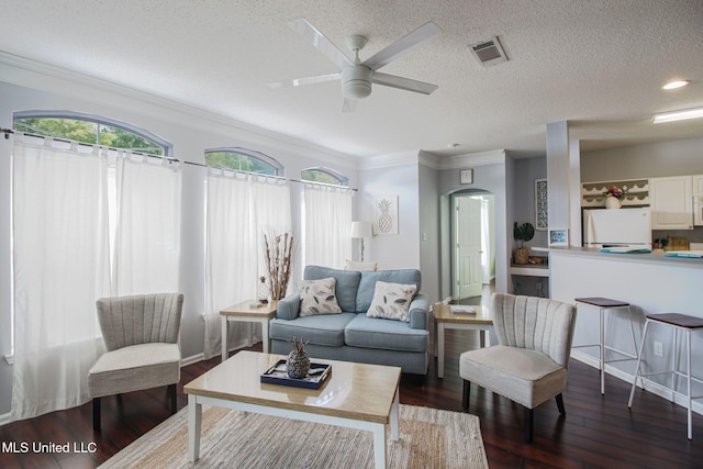 living room featuring dark wood-type flooring, ceiling fan, ornamental molding, and a textured ceiling