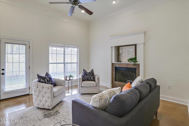 living room with a tile fireplace, ceiling fan, and ornamental molding