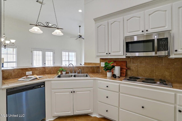 kitchen with stainless steel appliances, sink, decorative light fixtures, white cabinets, and plenty of natural light