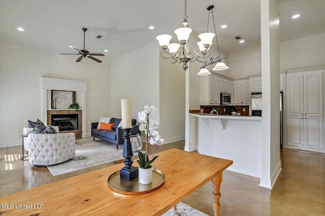 dining space featuring crown molding, concrete flooring, and ceiling fan with notable chandelier