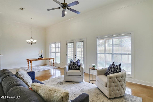 living room with ceiling fan with notable chandelier, a healthy amount of sunlight, a towering ceiling, and french doors