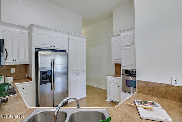 kitchen featuring decorative backsplash, white cabinetry, sink, and appliances with stainless steel finishes