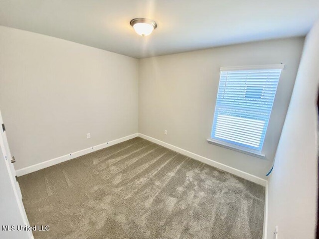 unfurnished room featuring carpet and baseboards