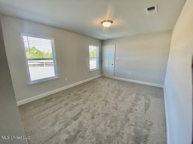 carpeted empty room with visible vents and baseboards