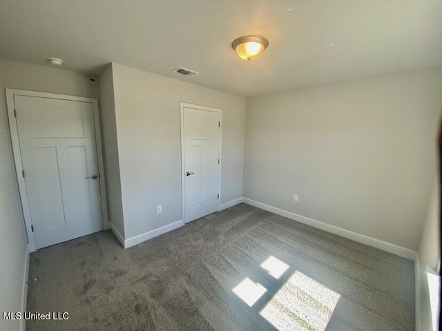 unfurnished bedroom featuring baseboards, carpet floors, and visible vents