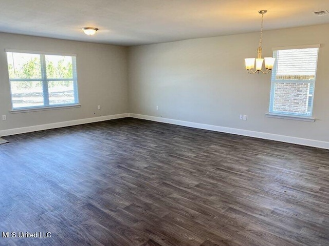 unfurnished room featuring a notable chandelier, baseboards, dark wood-type flooring, and visible vents