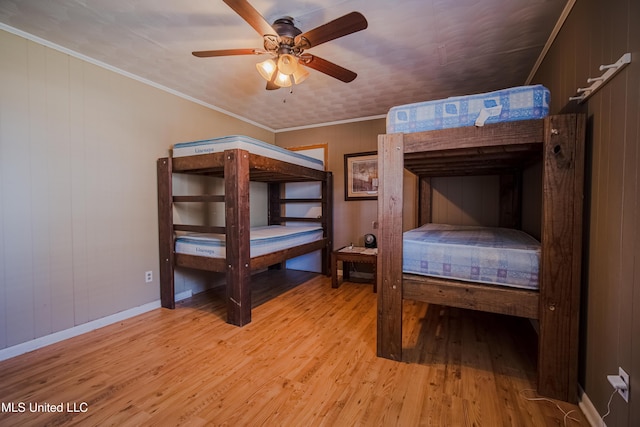 bedroom featuring a ceiling fan, light wood finished floors, baseboards, and ornamental molding