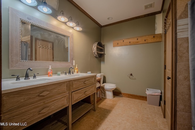 bathroom featuring toilet, crown molding, a sink, and visible vents