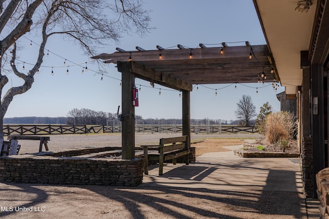 view of patio / terrace featuring a pergola, fence, and a rural view