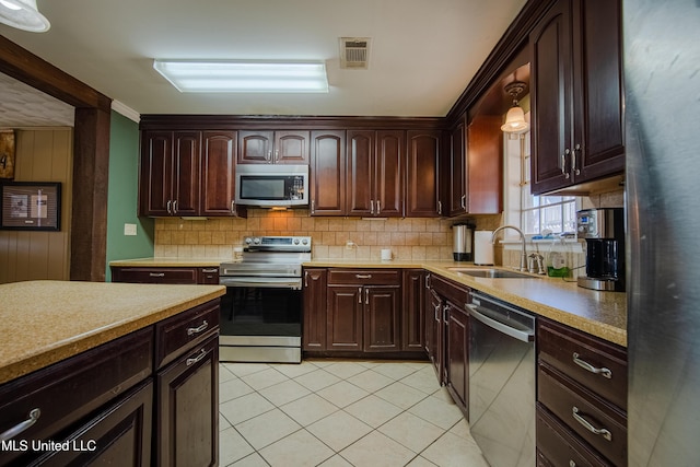 kitchen with visible vents, light tile patterned flooring, a sink, stainless steel appliances, and decorative backsplash