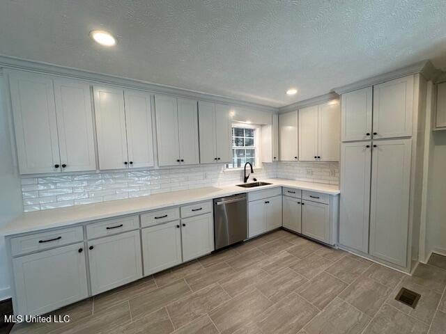 kitchen featuring stainless steel dishwasher, sink, decorative backsplash, and white cabinets