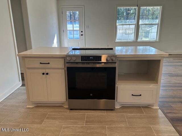 kitchen featuring white cabinetry, stainless steel electric range oven, and plenty of natural light